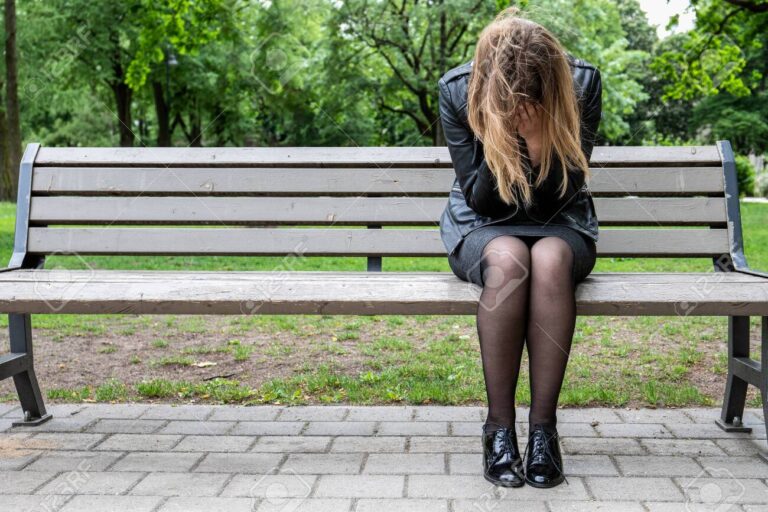Desperate, crying woman sitting on the bench at the park